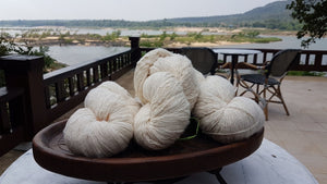 Yarn balls of sustainable, natural cotton with the Mekong River in the background. The image is taken at Tohsang Sustainable Cotton Village in Thailand for Rare & Fair.