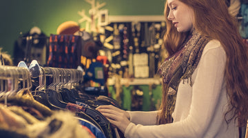 Side view of a woman in a shop looking through clothes hanging on a rail
